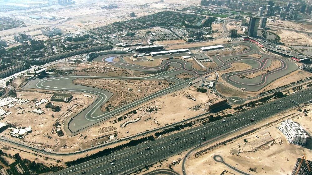 Aerial view of the Dubai Autodrome racing circuit in Motor City, Dubai, with the surrounding community and Sheikh Mohammed bin Zayed Road