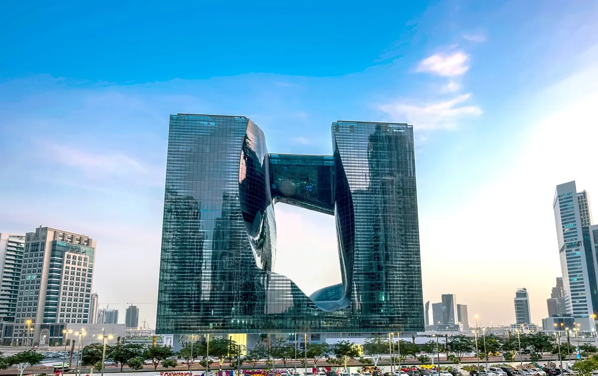 The Opus in Business Bay, Dubai — the glass cube with the void carved through its centre and the bridge linking the two towers above it.